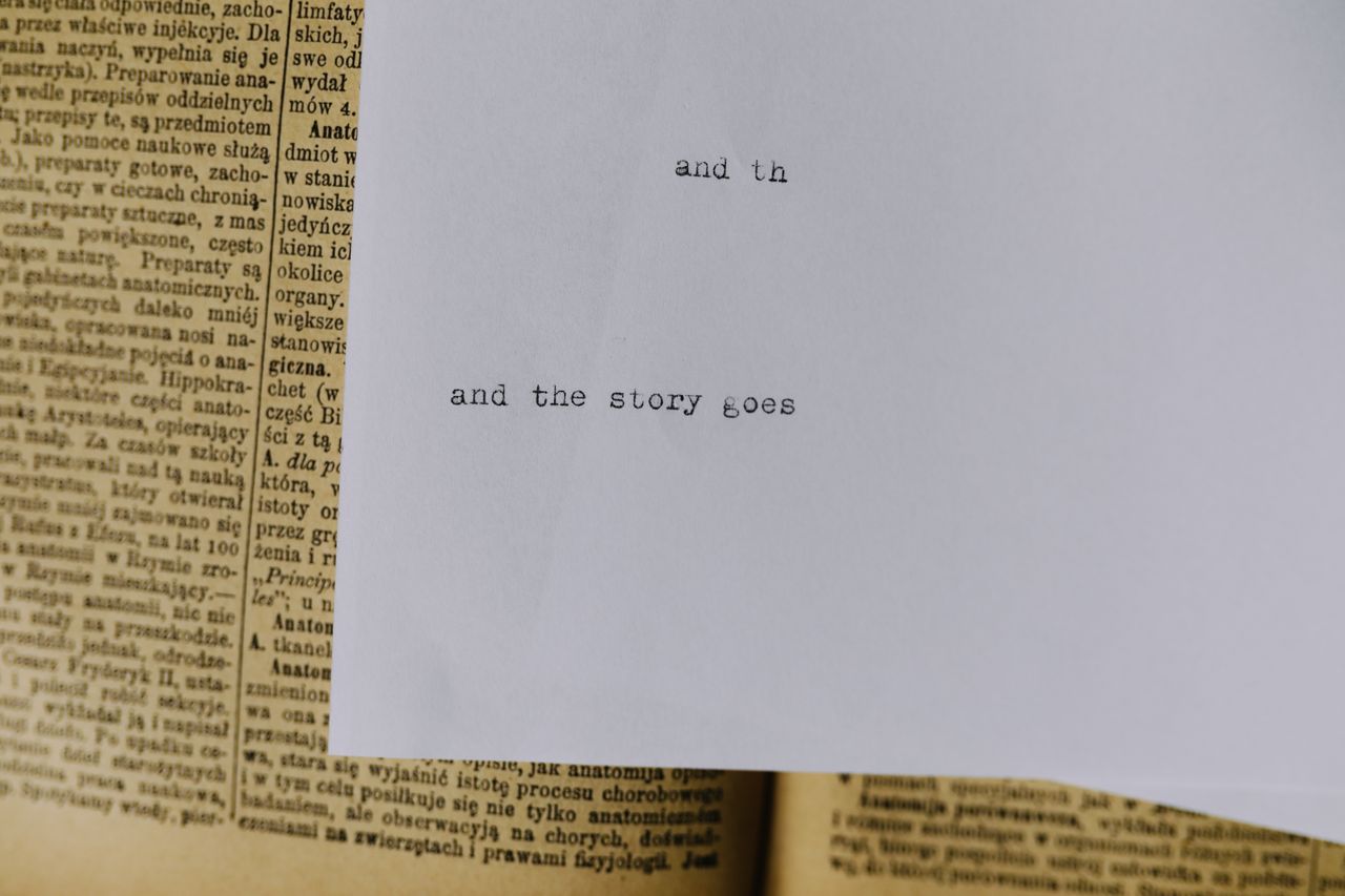 A piece of paper with typewritten text and the story goes over an old book page.